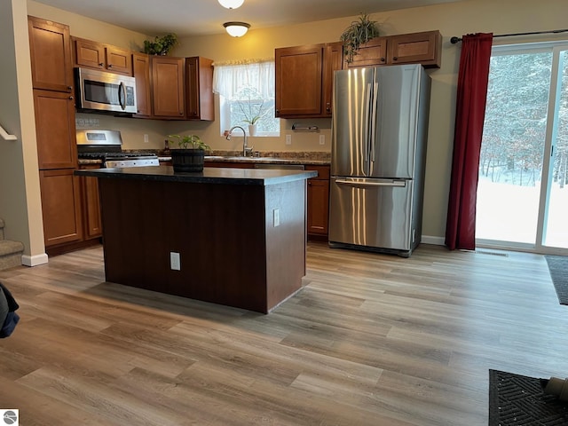 11893 Lillian Lee Dr, Interlochen, MI 49643 - kitchen featuring appliances with stainless steel finishes, a center island, a sink, light wood-style floors, and dark countertops