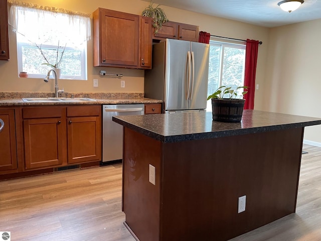 11893 Lillian Lee Dr, Interlochen, MI 49643 - kitchen featuring appliances with stainless steel finishes, a sink, dark countertops, and light wood-type flooring