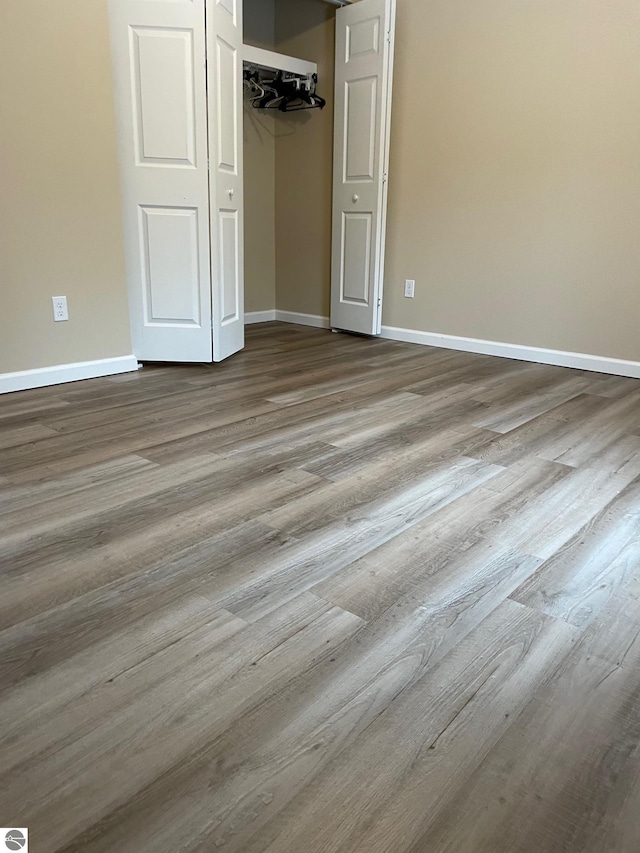 11893 Lillian Lee Dr, Interlochen, MI 49643 - unfurnished bedroom with baseboards, wood finished floors, and a closet