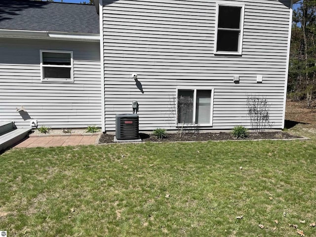 11893 Lillian Lee Dr, Interlochen, MI 49643 - rear view of house featuring a yard, central air condition unit, and a shingled roof