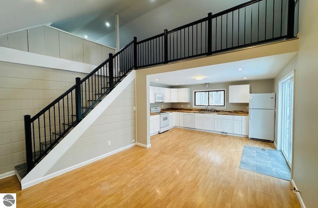 730 M-55, Boon, MI 49618 - kitchen with white cabinetry, white appliances, wooden walls, light wood finished floors, and a towering ceiling