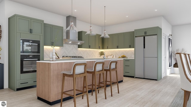 4480 Wolverine Dr Unit 22, Williamsburg, MI 49690 - kitchen featuring wall chimney range hood, light countertops, light wood-style flooring, freestanding refrigerator, and green cabinetry