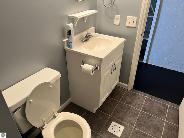 half bath featuring tile patterned floors, toilet, and vanity