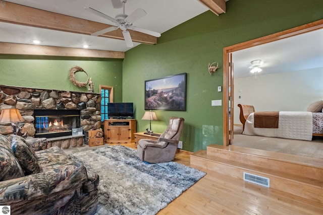 living area featuring visible vents, lofted ceiling with beams, wood finished floors, a fireplace, and ceiling fan