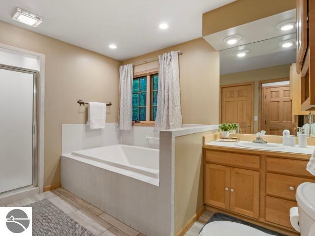 bathroom featuring vanity, recessed lighting, a shower stall, a garden tub, and toilet