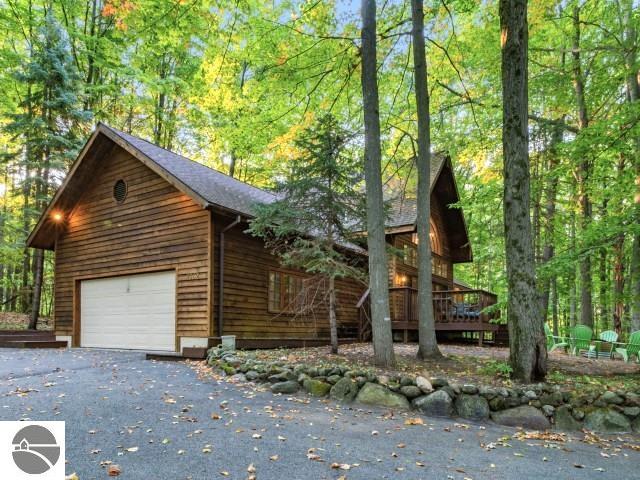 view of side of home featuring a view of trees, a garage, and driveway