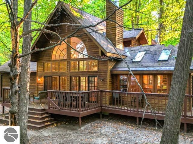 back of property with a chimney, a deck, and a shingled roof