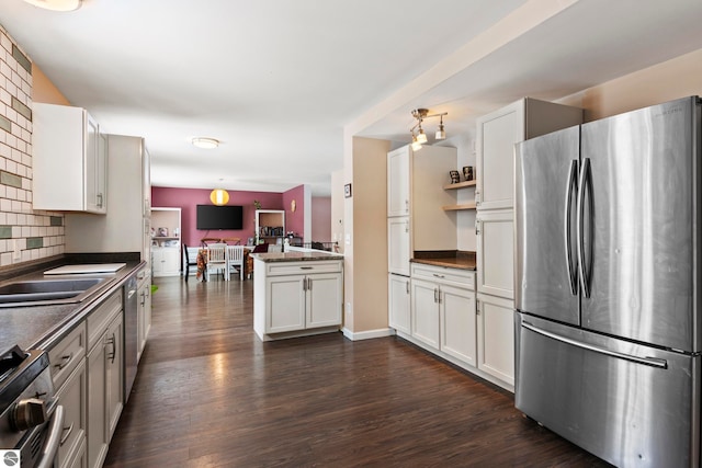kitchen with dark countertops, tasteful backsplash, dark wood finished floors, stainless steel appliances, and white cabinetry