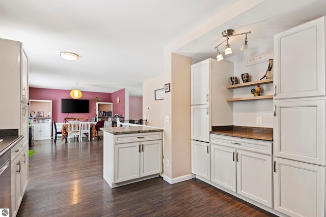 kitchen featuring dark stone counters, open floor plan, a peninsula, and dark wood finished floors