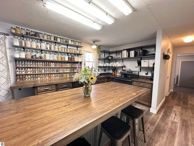 bar featuring baseboards, dark wood-style floors, bar area, and stainless steel electric range oven