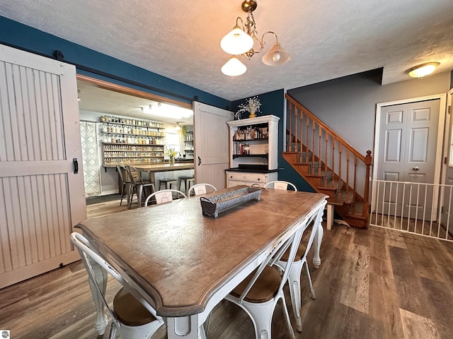 dining room featuring a bar, a textured ceiling, and wood finished floors