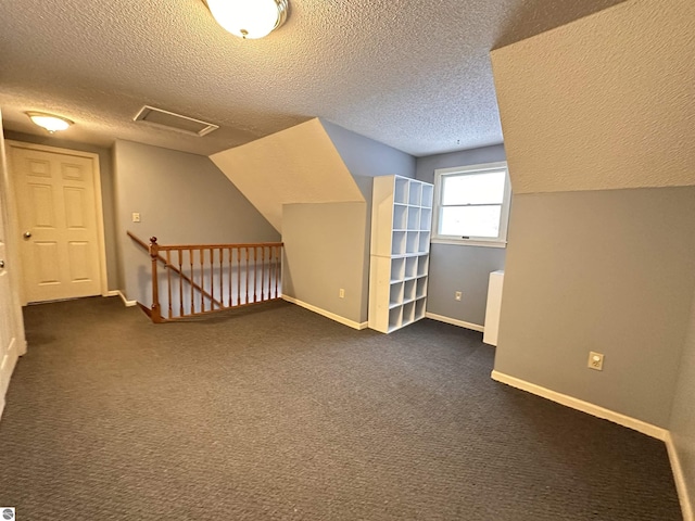 bonus room featuring baseboards, vaulted ceiling, dark colored carpet, and a textured ceiling