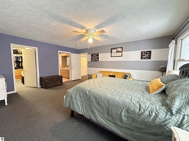carpeted bedroom with a ceiling fan, a walk in closet, baseboards, and a textured ceiling
