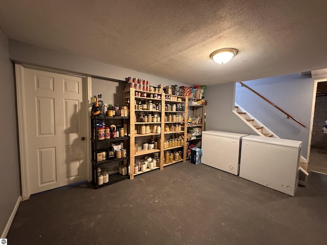 finished below grade area with refrigerator, white fridge, stairs, and a textured ceiling