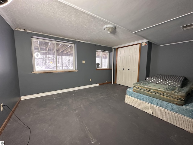 unfurnished bedroom with a closet, a textured ceiling, baseboards, visible vents, and concrete flooring