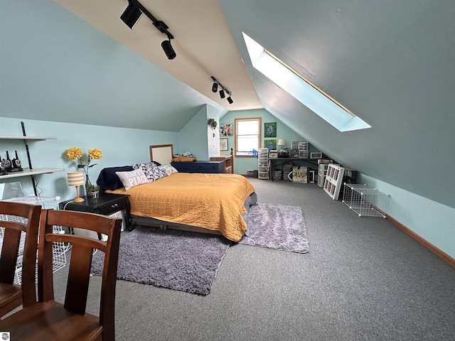 carpeted bedroom with track lighting, baseboards, and vaulted ceiling with skylight