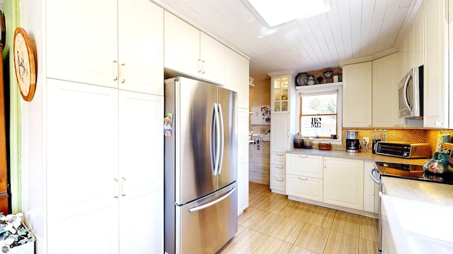 17429 Summit Ct, Barryton, MI 49305 - kitchen featuring appliances with stainless steel finishes, light countertops, white cabinetry, tasteful backsplash, and a skylight