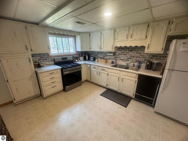 kitchen with a sink, freestanding refrigerator, light floors, black dishwasher, and stainless steel range with gas cooktop