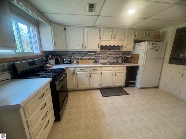 kitchen with light countertops, range with gas cooktop, a sink, dishwasher, and freestanding refrigerator