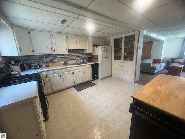 kitchen featuring light countertops, freestanding refrigerator, tasteful backsplash, dishwasher, and light floors