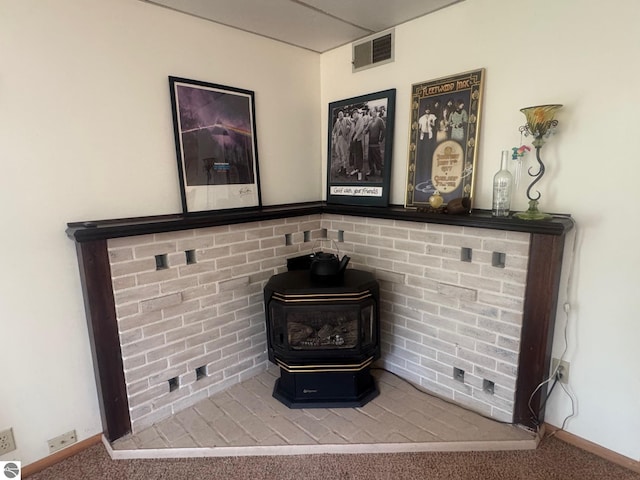 room details with baseboards, visible vents, a wood stove, and carpet flooring