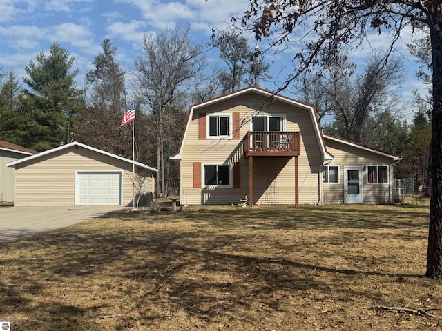 colonial inspired home featuring a gambrel roof, an outbuilding, concrete driveway, a detached garage, and a front lawn