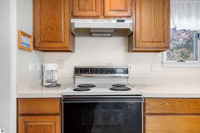 3275 S Sunrise Ln, Lake Leelanau, MI 49653 - kitchen with under cabinet range hood, range with electric cooktop, light countertops, and brown cabinetry