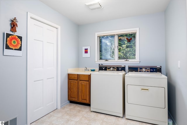3275 S Sunrise Ln, Lake Leelanau, MI 49653 - clothes washing area featuring a sink, light tile patterned floors, independent washer and dryer, visible vents, and cabinet space