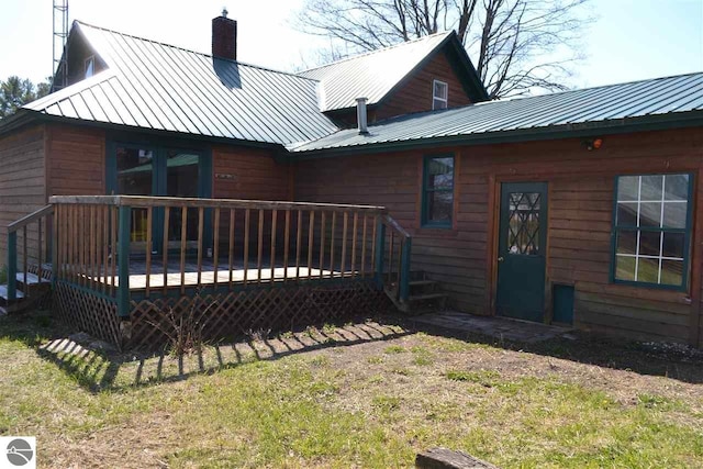 back of house with metal roof, a chimney, and a wooden deck