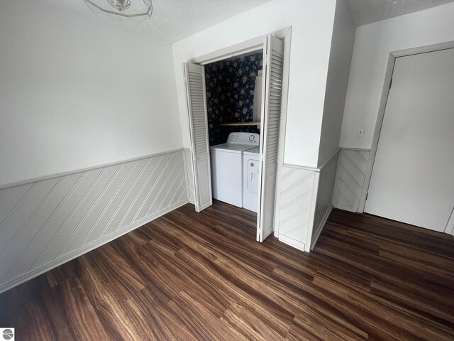 empty room featuring dark wood-style floors, wainscoting, washer and dryer, and a textured ceiling