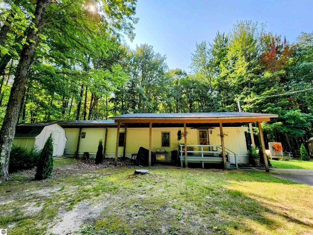 8468 Shorewood Ct, Mancelona, MI 49659 - view of front facade with a porch, an outbuilding, a front lawn, and a storage shed