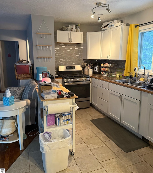 6133 W Airline Rd, Weidman, MI 48893 - kitchen with stainless steel range with gas stovetop, decorative backsplash, white cabinets, and a sink