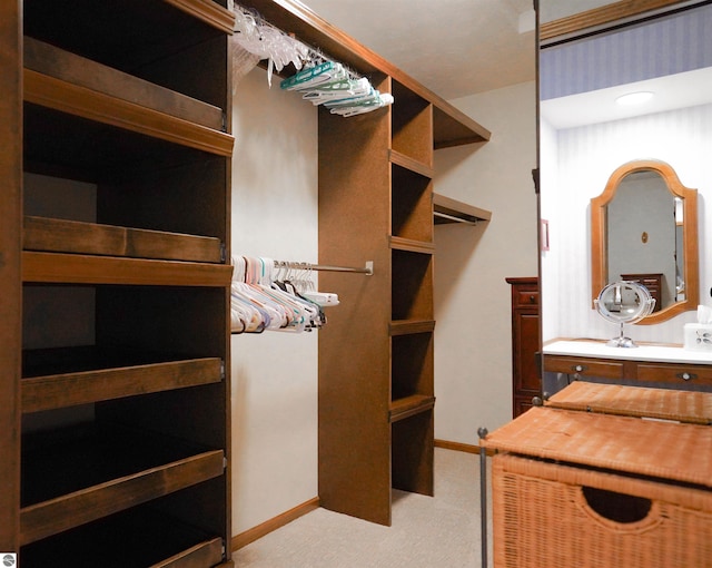walk in closet with light carpet