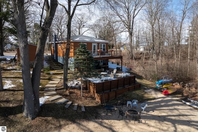 9701 S Lake Station Ave, Lake, MI 48632 - rear view of house with an outdoor fire pit, a deck, stairs, and metal roof