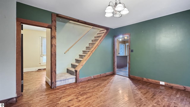 interior space with a chandelier, baseboards, stairs, and wood finished floors