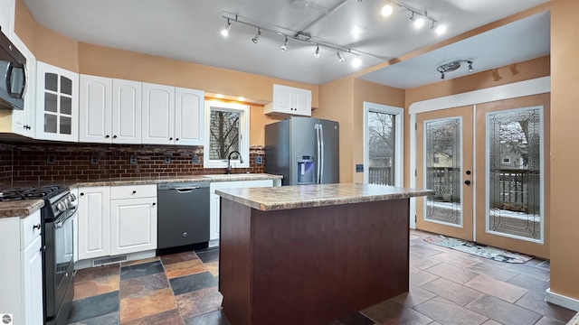 kitchen with a center island, black appliances, a sink, and tasteful backsplash