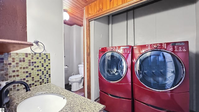 laundry area featuring wood ceiling, independent washer and dryer, a sink, and laundry area