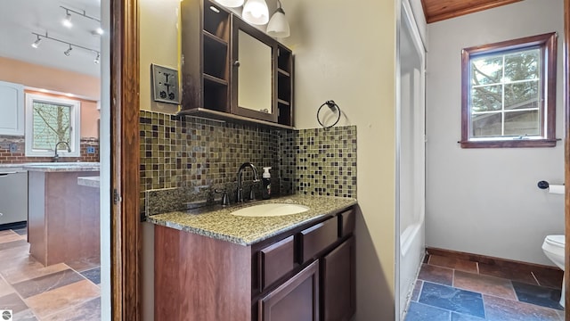 full bathroom with vanity, toilet, baseboards, backsplash, and stone tile flooring