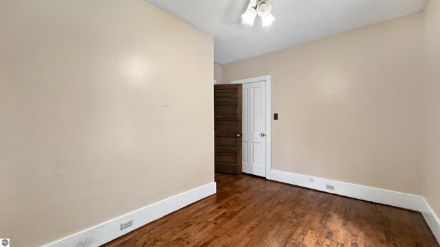 unfurnished room with baseboards, a textured ceiling, and wood finished floors