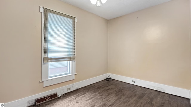 unfurnished room with baseboards, visible vents, and wood finished floors