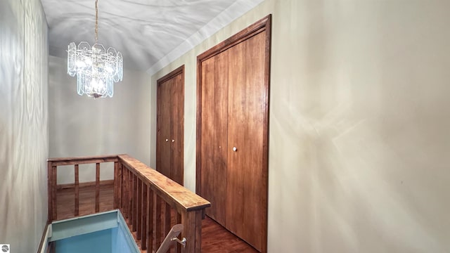 hallway featuring an upstairs landing, a notable chandelier, and dark wood finished floors
