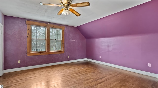 additional living space featuring baseboards, lofted ceiling, wood finished floors, and a ceiling fan