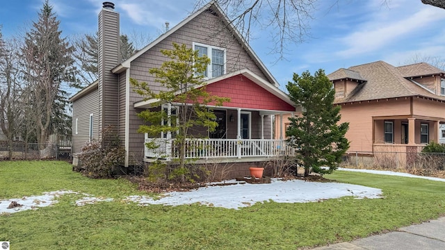 view of front of house with a chimney, fence, a front lawn, and a porch
