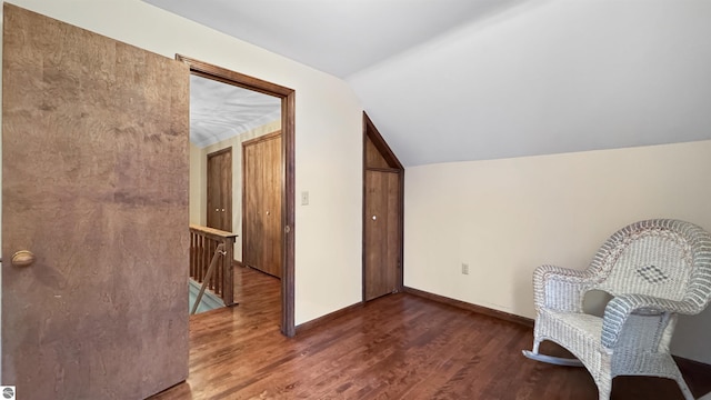 unfurnished room with baseboards, vaulted ceiling, wood finished floors, and an upstairs landing