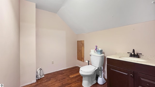 half bathroom with vaulted ceiling, toilet, vanity, wood finished floors, and baseboards