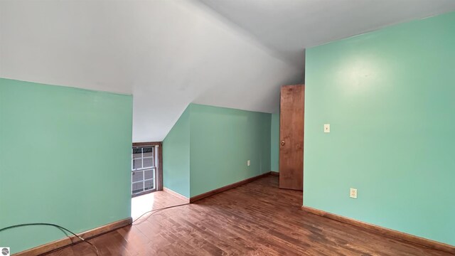 additional living space with baseboards, lofted ceiling, and wood finished floors