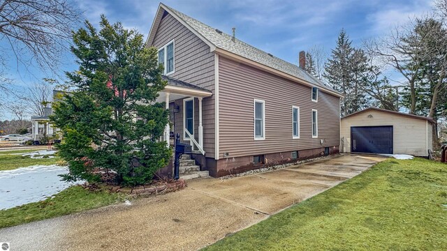 view of side of property with driveway, a detached garage, a lawn, and an outdoor structure