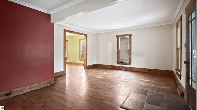 empty room featuring baseboards, wood finished floors, and crown molding