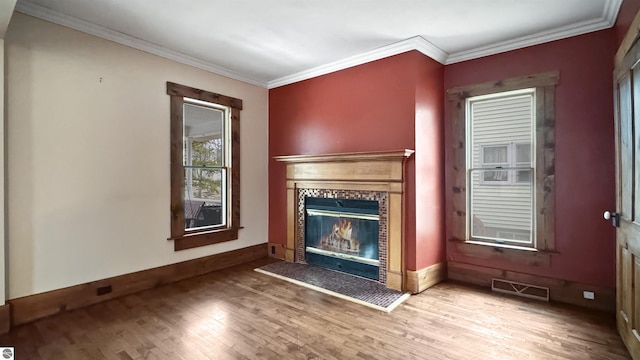 unfurnished living room with crown molding, baseboards, visible vents, a tile fireplace, and wood finished floors