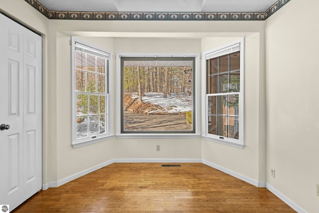 unfurnished dining area featuring baseboards, visible vents, and wood finished floors